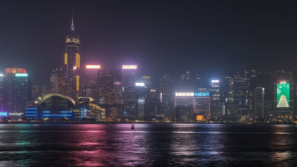 Wan Chai skyline lit up at night across Victoria Harbour, seen from Tsim Sha Tsui